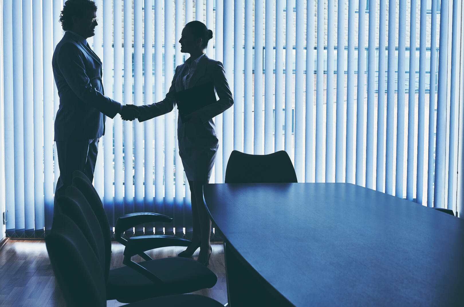 Two people shaking hands in a conference room